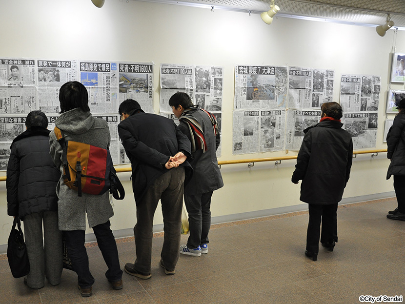 画像：市役所本庁舎１階で被害を報じる新聞を見つめる市民